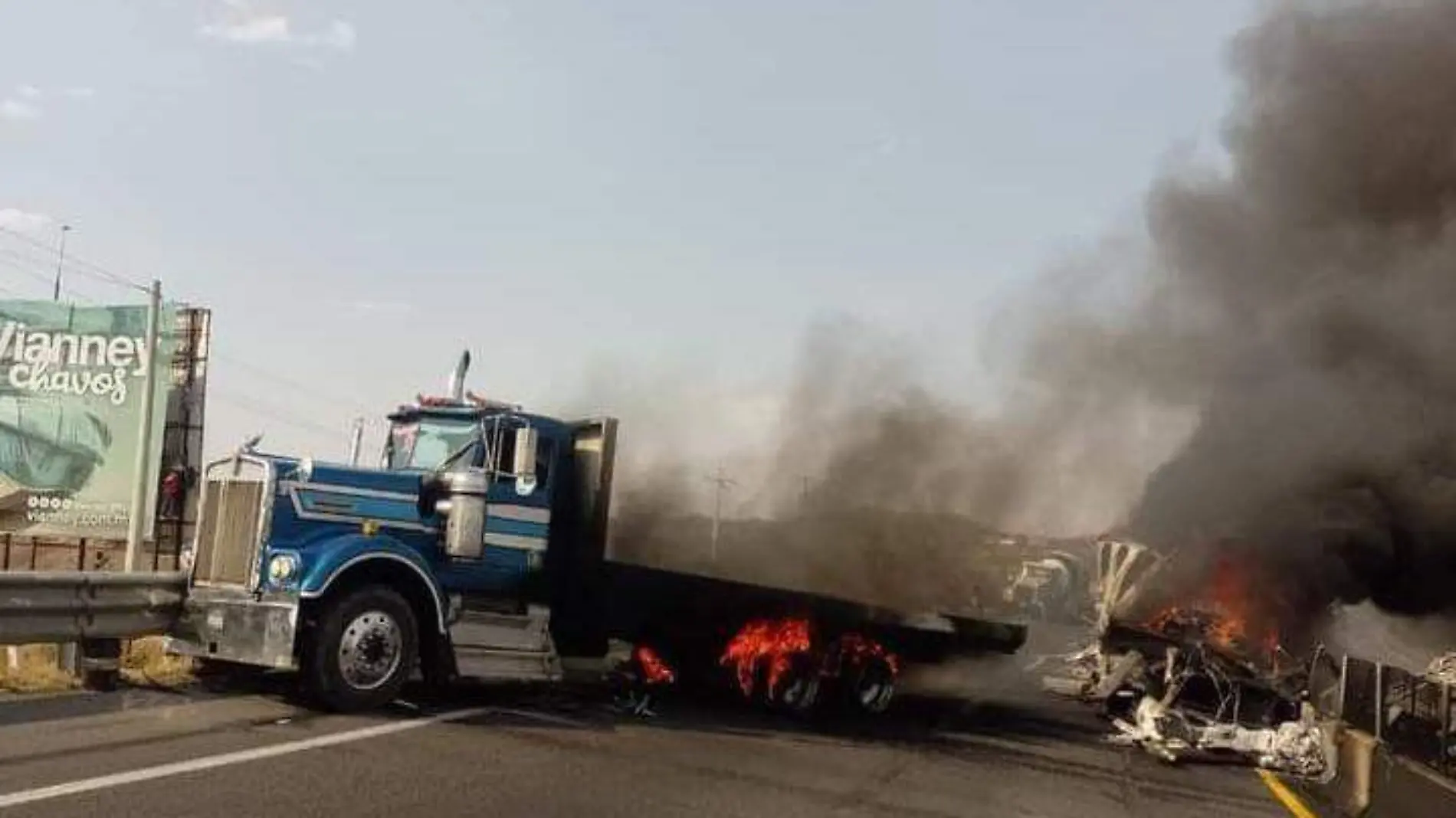 Tráiler y vehículo incendiado sobre autopista